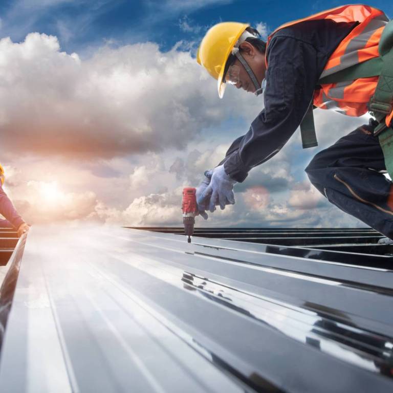 worker builder with hand drill at metal profile roof installatio worker builder with hand drill at metal profile roof installation Metal roof construction